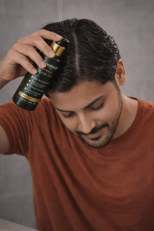 Rootsyra Herbal Hair Oil being pumped from the bottle onto the scalp during application.